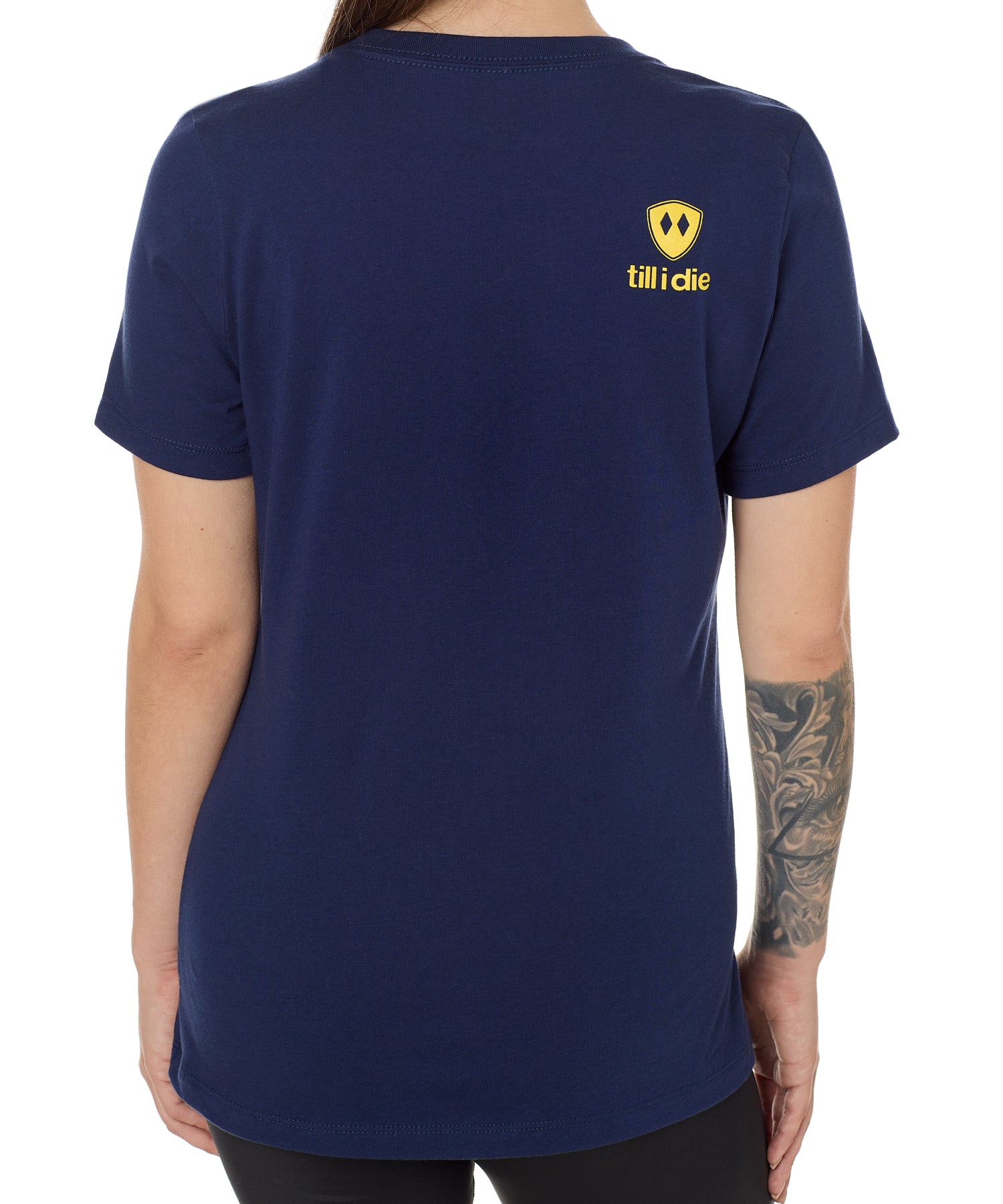 Back view of a female model wearing a navy tee shirt accented with a yellow till i die logo on wearers top right shoulder.