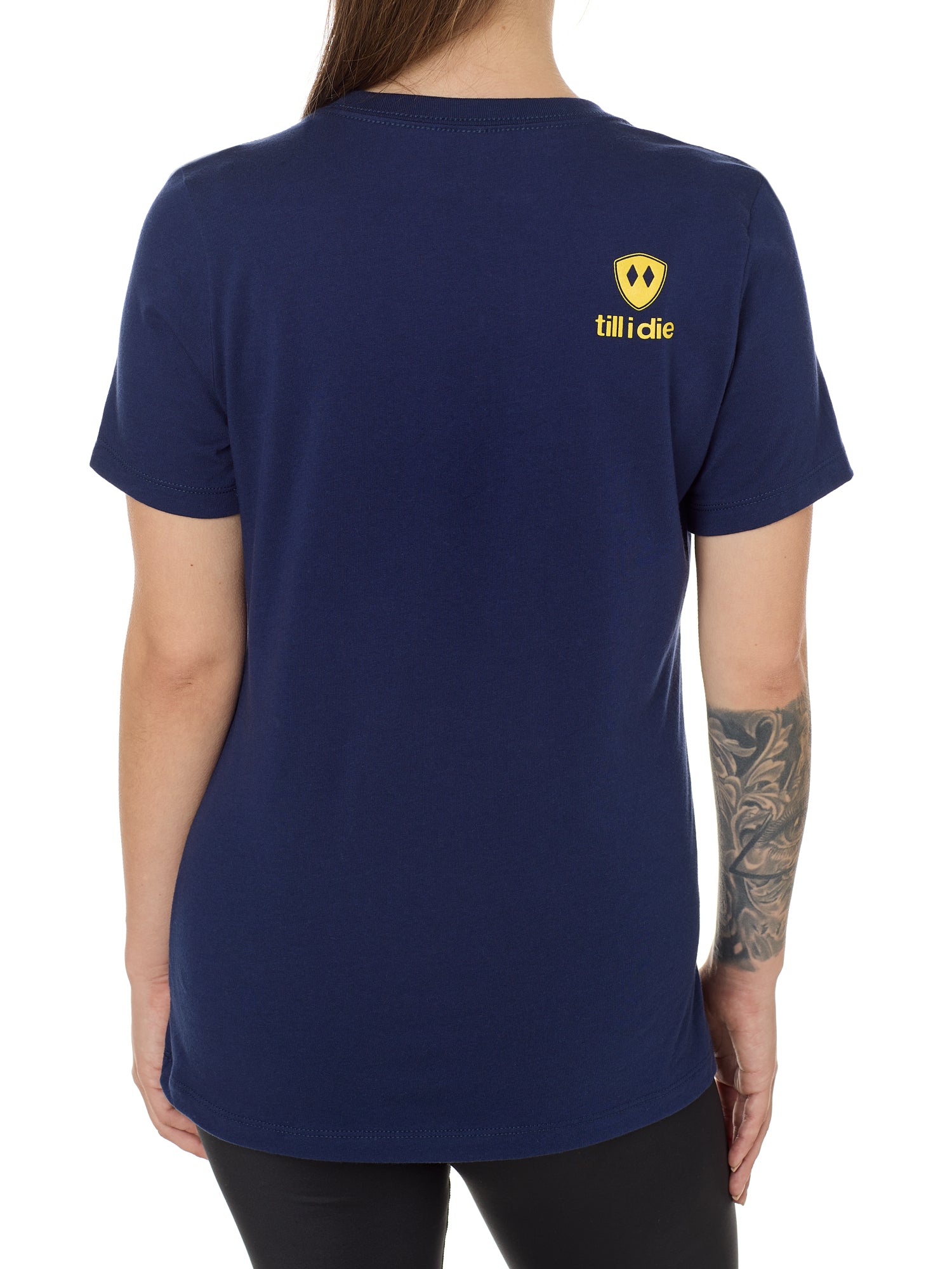 Back view of a female model wearing a navy tee shirt accented with a yellow till i die logo on wearers top right shoulder.