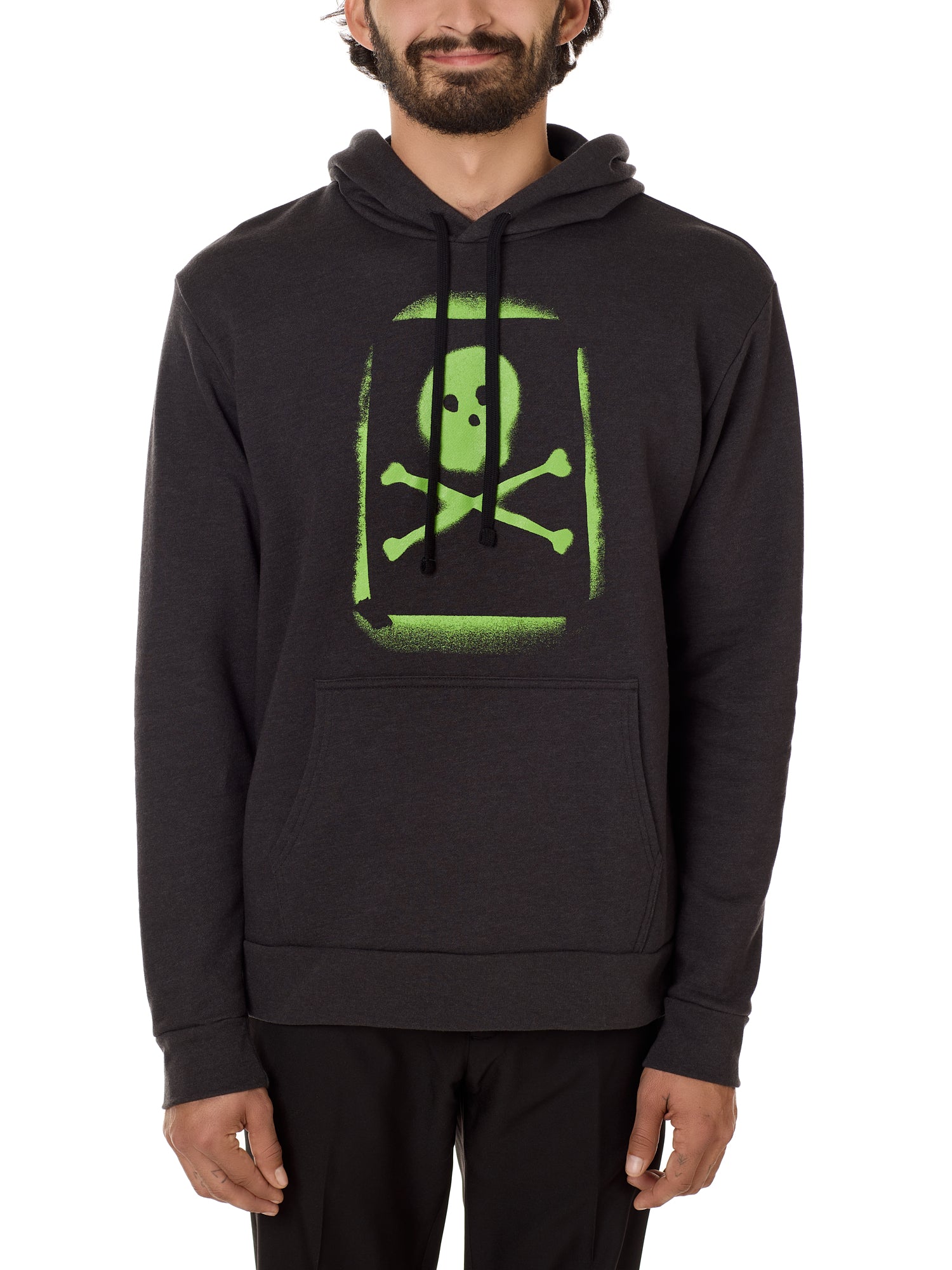 A male model wearing a black hoodie with a bold, green skull and crossbones design on the front.