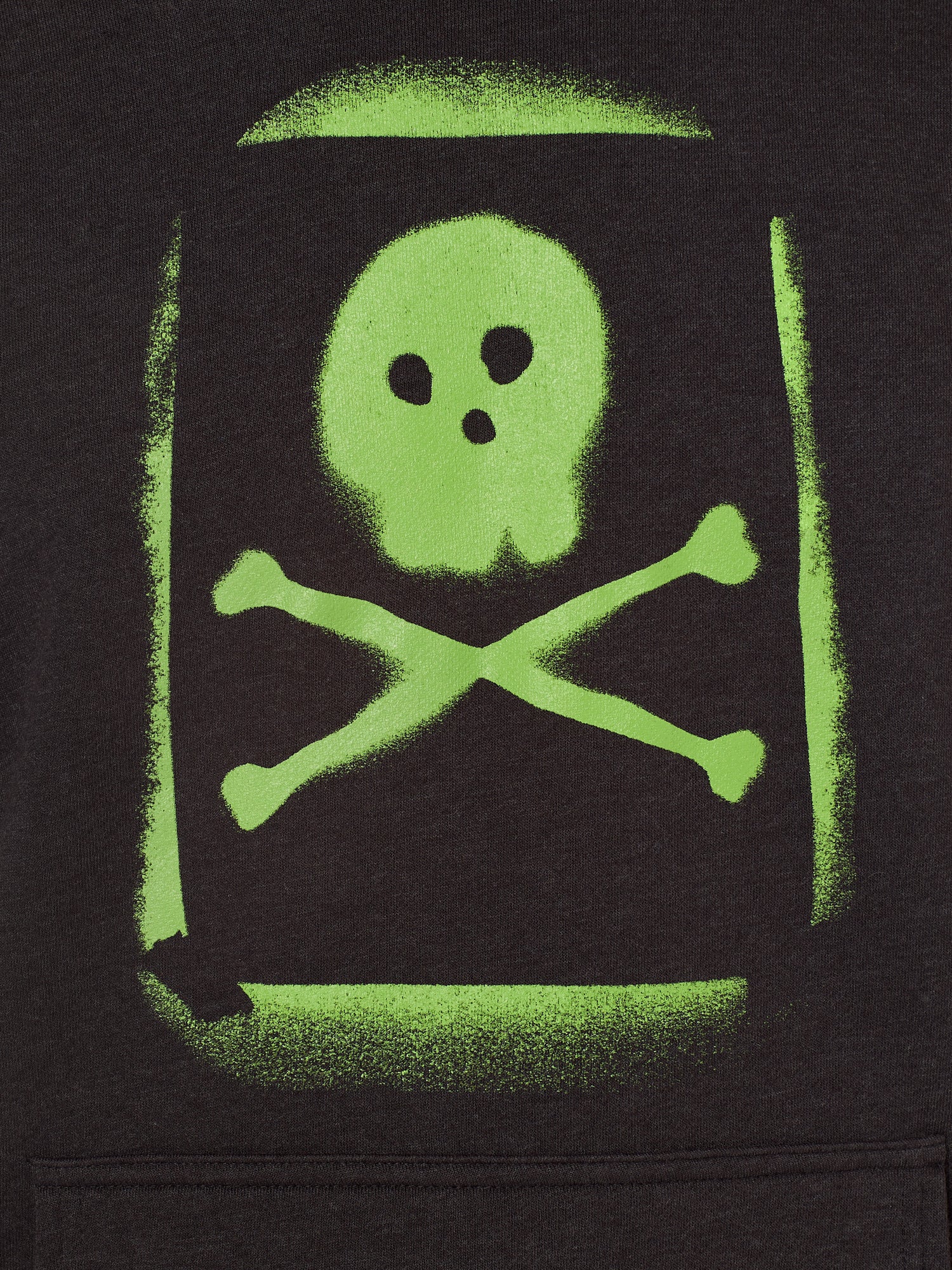 Detail of the Graffiti hoodie in Black, featuring a lime green spray painted style design of a skull and crossbones with overspray accents