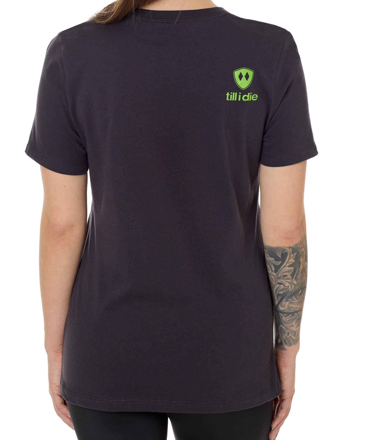 Back view of a female model wearing a dark gray tee shirt accented with a lime green till i die logo on wearers top right shoulder.