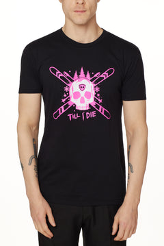 Front view of a male model wearing the ULLR black crew neck tee on a white background. The pink and white graphic features a skull over crossed skis, with snowflakes, pine trees, and “Till I Die” text layered below.