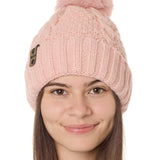 front view of a female model wearing a blush knit pom beanie featuring a matching pom pom, cuff and leather till i die logo tab with a nickel fastener.