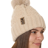 side view of a female model wearing a vintage white knit pom beanie featuring a matching pom pom, cuff and leather till i die logo tab with a nickel fastener.