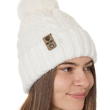 side view of a female model wearing a white knit pom beanie featuring a matching pom pom, cuff and leather till i die logo tab with a nickel fastener.