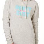 FEMALE MODEL WEARING A HEATHER OATMEAL HOODIE WITH A PINK AND BLUE GRAHIC THAT SAYS BEAST OF THE EAST