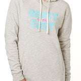 FEMALE MODEL WEARING A HEATHER OATMEAL HOODIE WITH A PINK AND BLUE GRAHIC THAT SAYS BEAST OF THE EAST