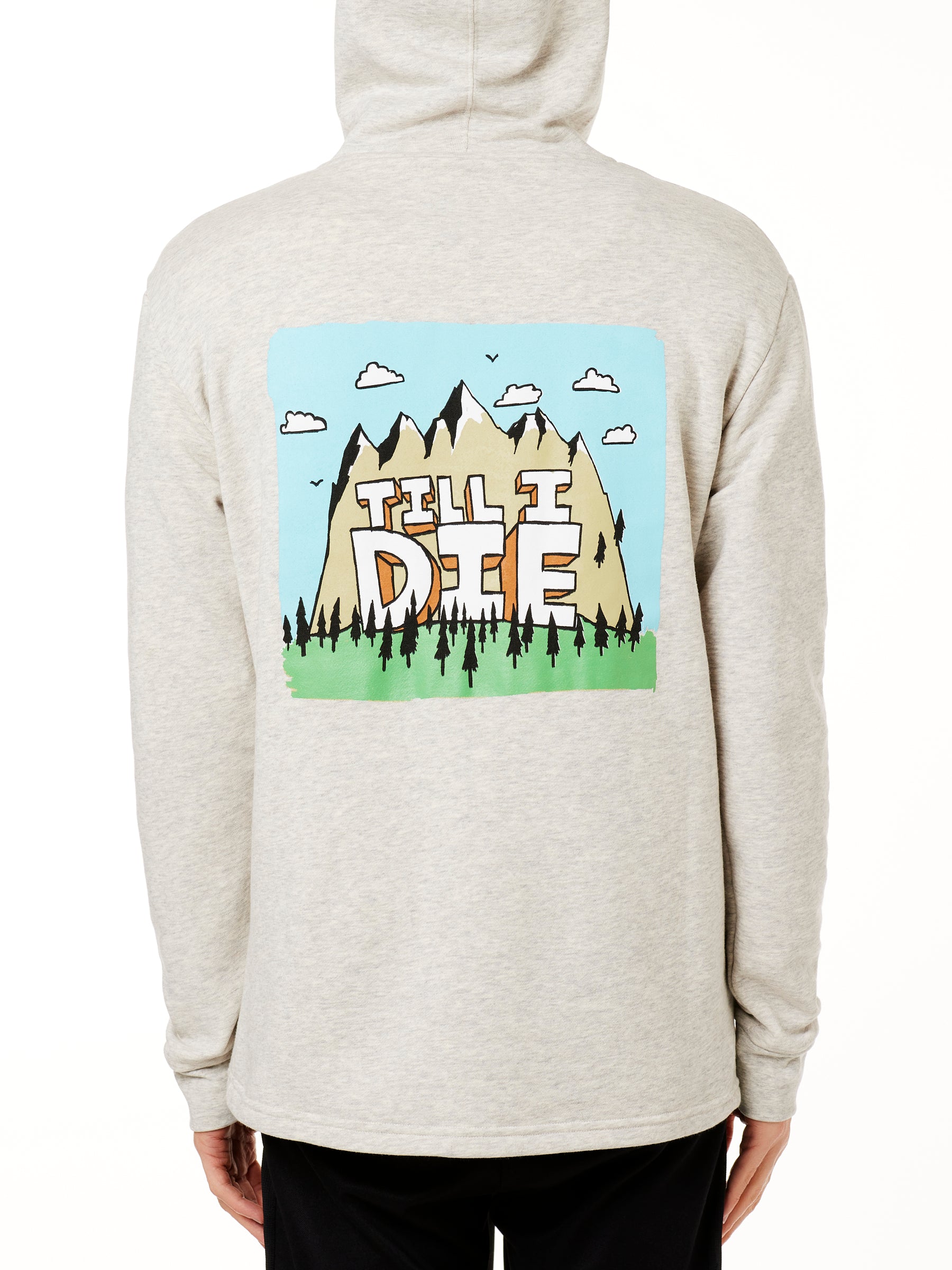MALE MODEL WEARING A HEATHER OATMEAL HOODIE WITH HOOD UP, FEATURING A GRAPHIC OF A CARTOON MOUNTAIN THAT HAS TILL I DIE ACROSS IT