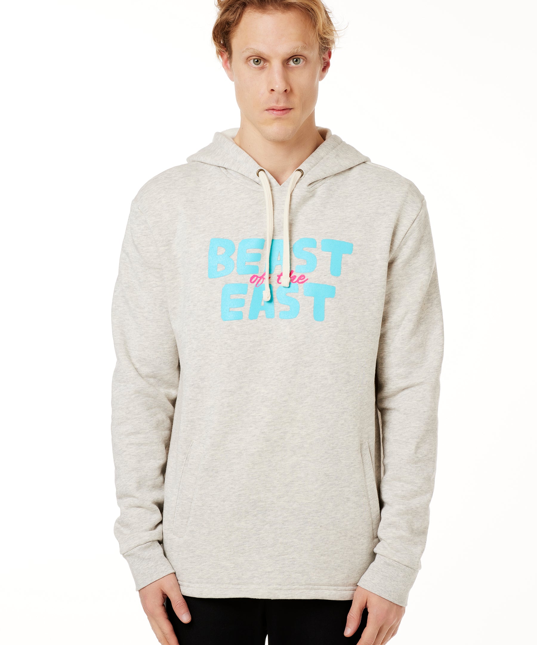 FEMALE MODEL WEARING A HEATHER OATMEAL HOODIE WITH A PINK AND BLUE GRAHIC THAT SAYS BEAST OF THE EAST