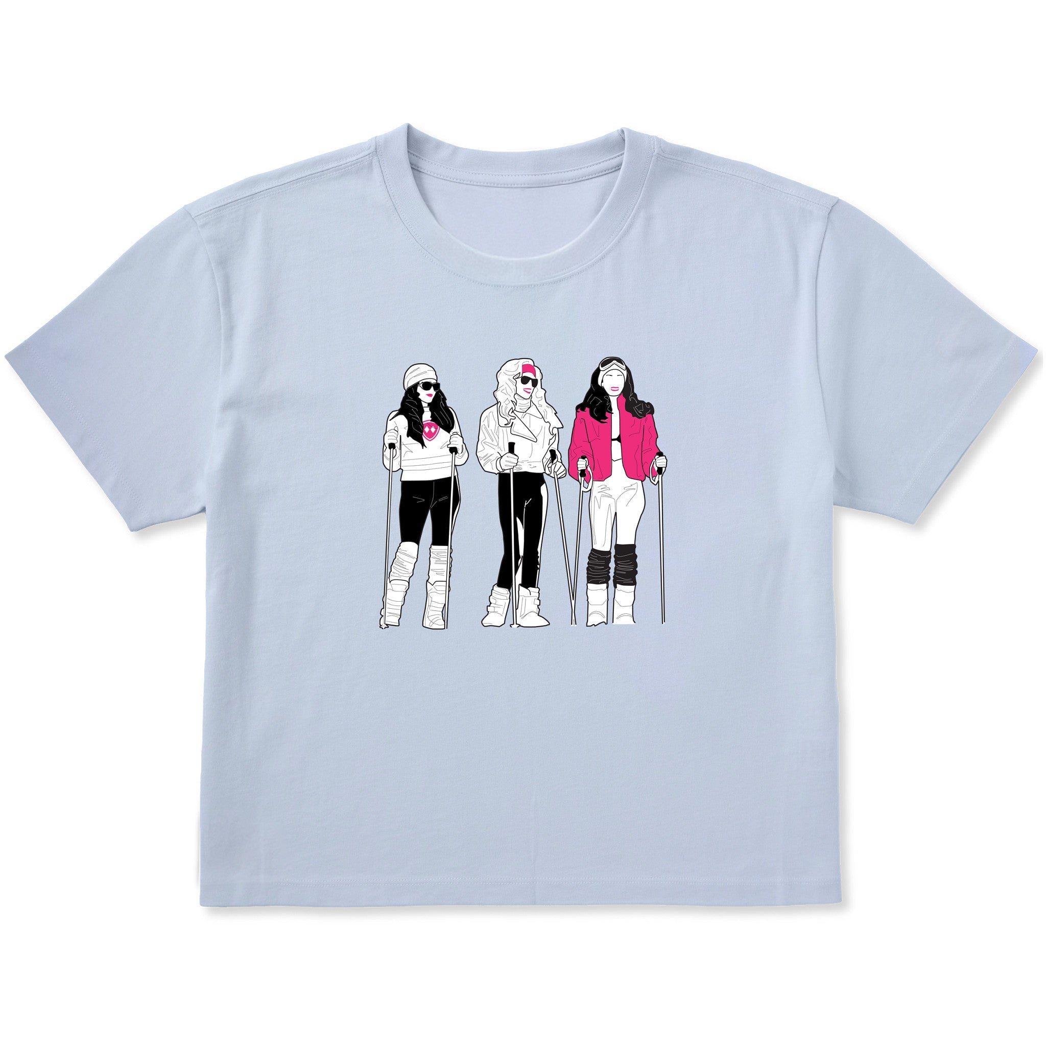 Light blue women’s cropped T-shirt featuring an illustrated trio of female skiers dressed in retro 1980s ski fashion, rendered in black and white with bold hot pink accents.