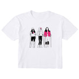 White women’s cropped T-shirt featuring an illustrated trio of female skiers dressed in retro 1980s ski fashion, rendered in black and white with bold hot pink accents.