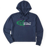 Navy crop hoodie featuring a neon green technical illustration of a ski binding with hot pink accents and a DIN setting cranked to 11, alongside bold white text reading, “Ask me about my DIN setting.”
