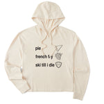 Cream cropped hoodie featuring black text and hand-drawn icons celebrating three mountain essentials: pie, French fries, and “Ski Till I Die,” finished with the signature Double Diamond shield.