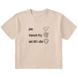 Cream cropped T-shirt featuring black text and hand-drawn icons celebrating three mountain essentials: pie, French fries, and “Ski Till I Die,” finished with the signature Double Diamond shield.