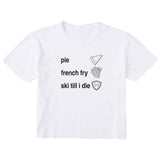 White cropped T-shirt featuring black text and hand-drawn icons celebrating three mountain essentials: pie, French fries, and “Ski Till I Die,” finished with the signature Double Diamond shield.