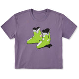 A purple short-sleeve crewneck t-shirt featuring a graphic print of two lime green rear entry ski boots in the center, displayed on a clean white background.