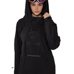 Model wearing black pullover with helmet and goggles, hands lifting hood collar, showcasing winter-ready design.