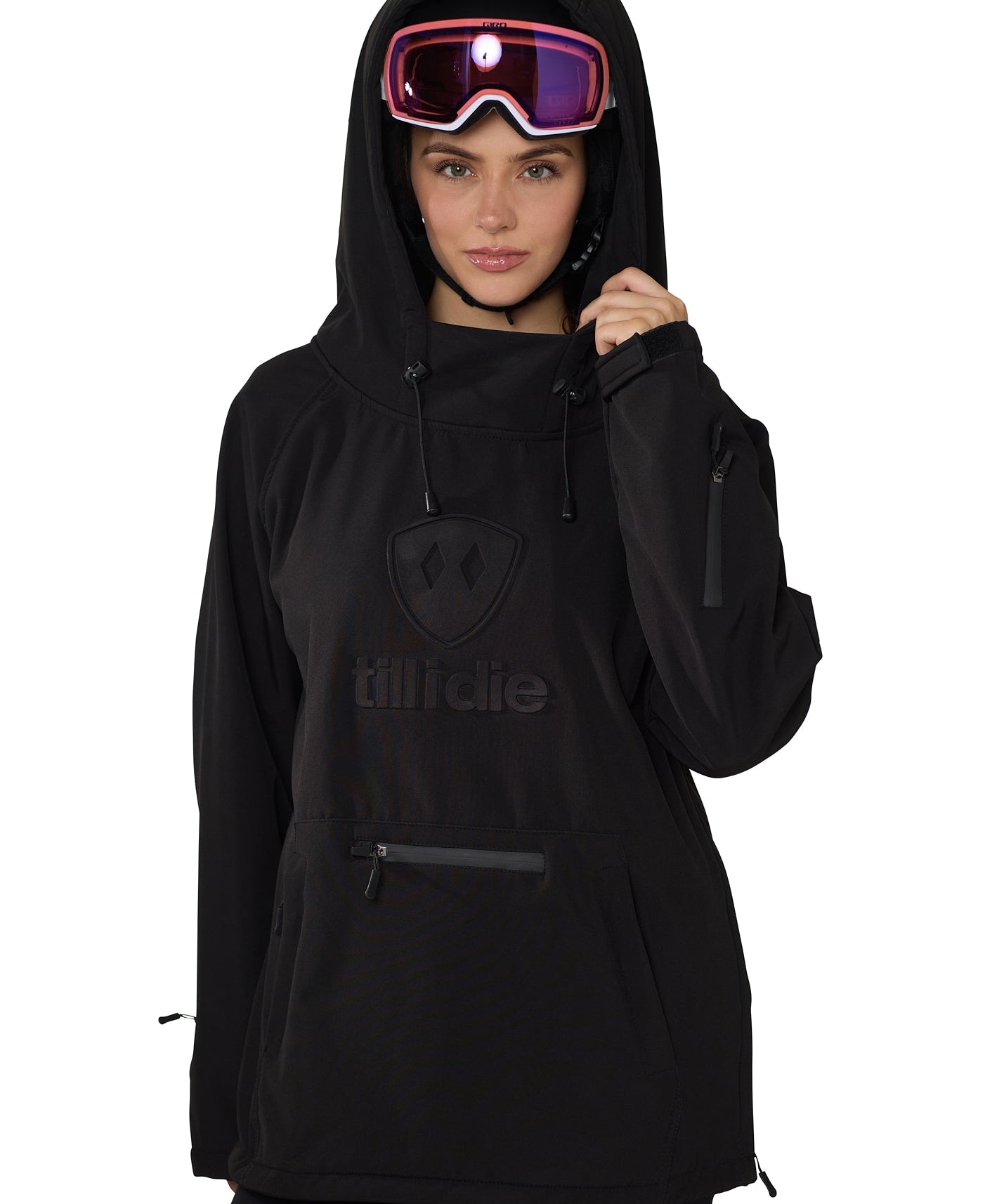 Model wearing black pullover with helmet and goggles, hands lifting hood collar, showcasing winter-ready design.