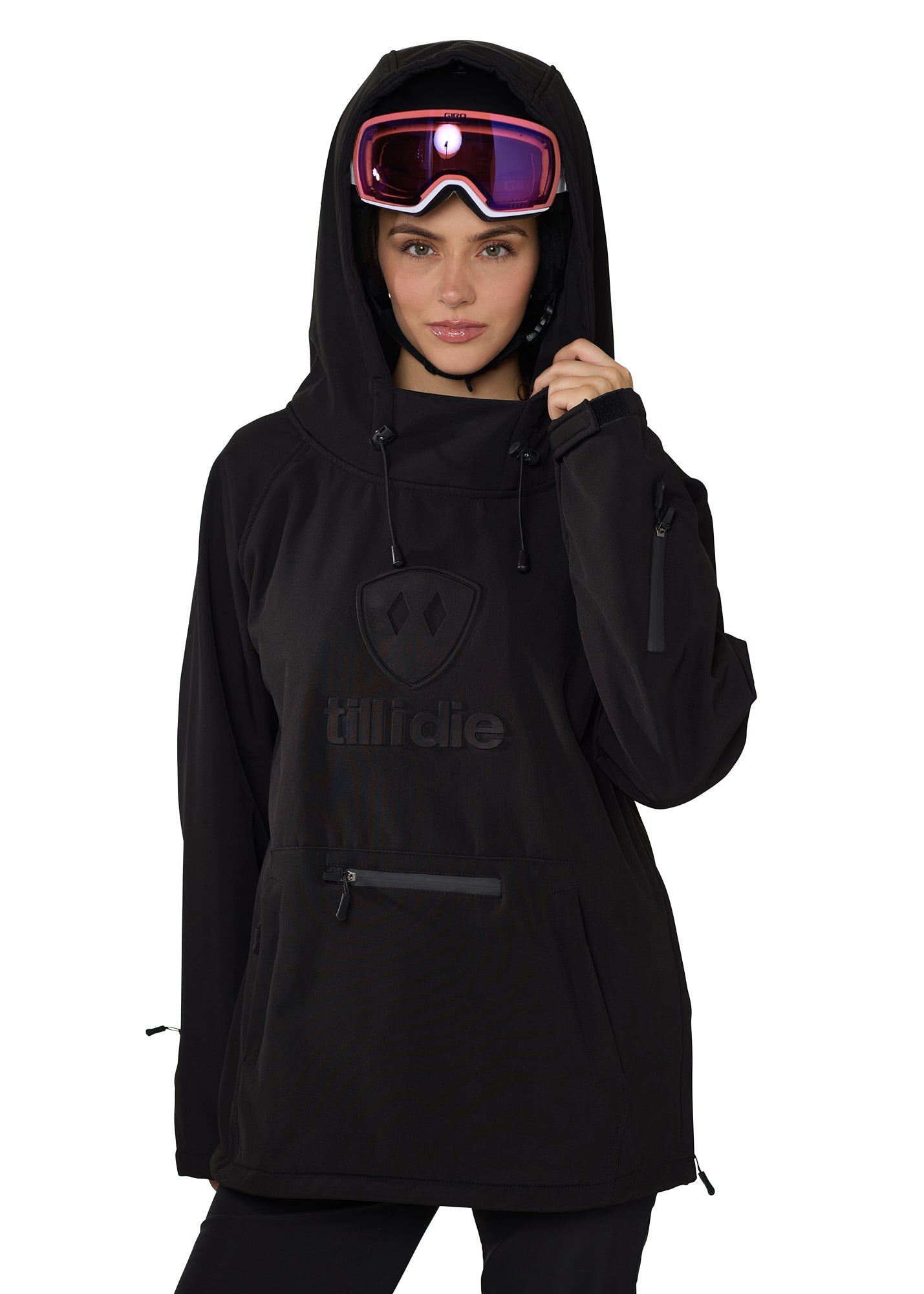 Model wearing black pullover with helmet and goggles, hands lifting hood collar, showcasing winter-ready design.