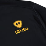 Close-up of Till I Die orange logo and double diamond shield on back of black long sleeve shirt
