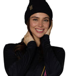 Person wearing a black outfit with a knkit pom beanie hat on a white background