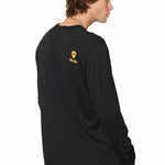 Back view of male model wearing black long sleeve featuring orange Till I Die logo and double diamond shield on shoulder