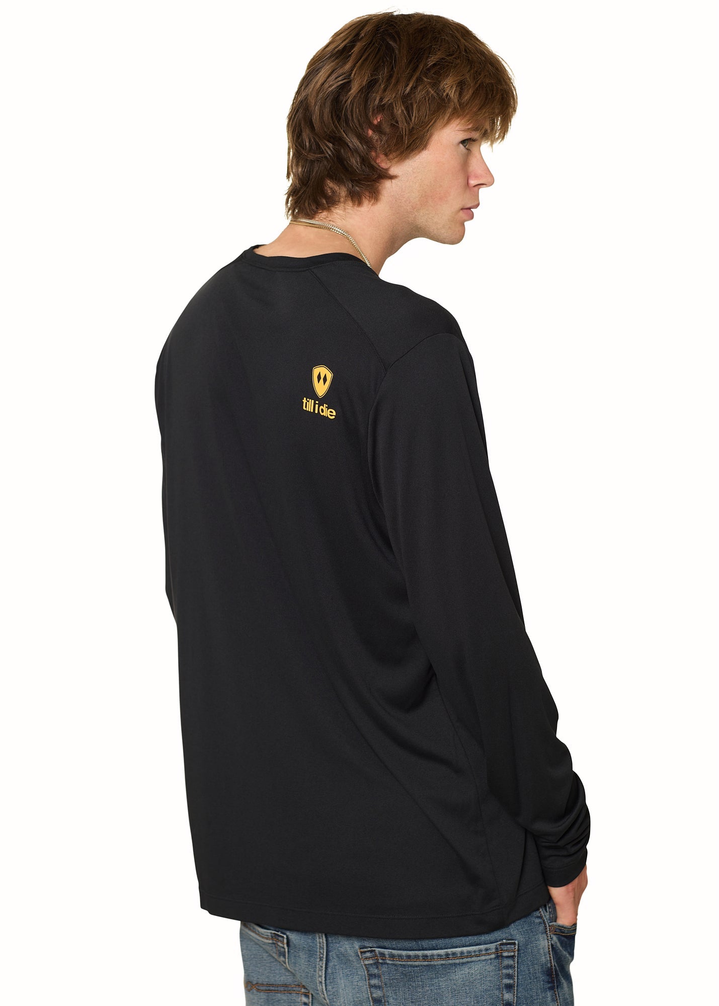 Back view of male model wearing black long sleeve featuring orange Till I Die logo and double diamond shield on shoulder