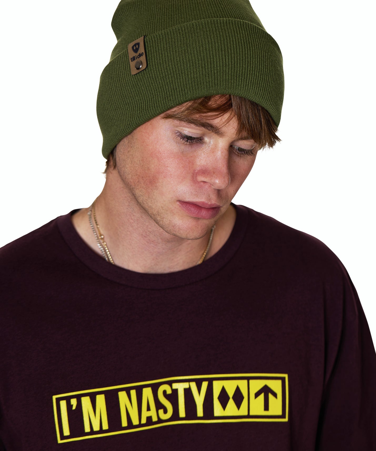Male Model wearing a military green beanie and a oxblood shirt with 'I'M NASTY' text in bright yellow on a white background