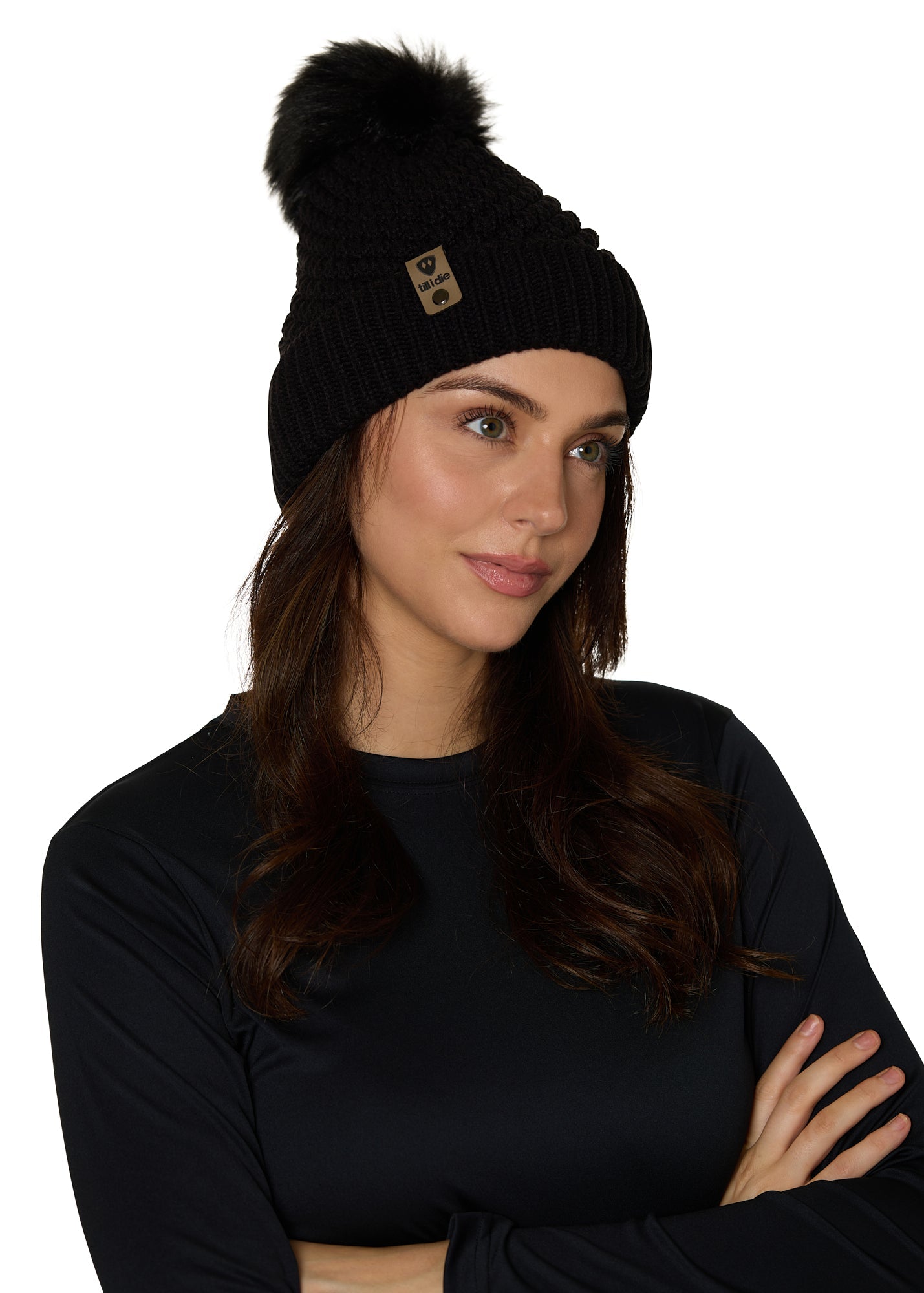 Female model wearing the Diamond Knit Pom Beanie in black, showcasing the faux fur pom and leather logo tab.