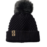Product flat lay of the Diamond Knit Pom Beanie in black, displaying the ribbed cuff, diamond knit design, and leather logo tab with faux fur pom.