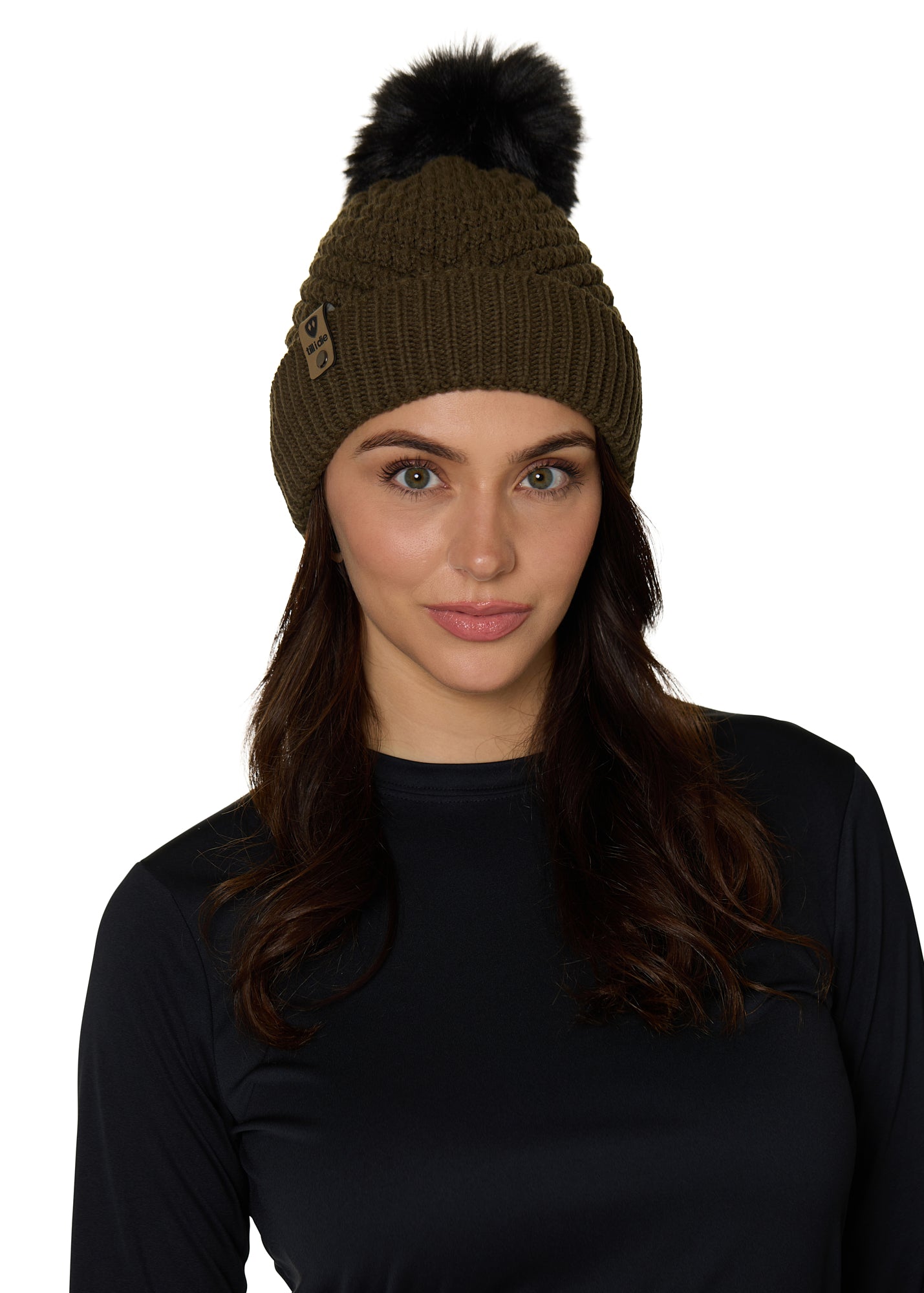 Female model wearing the Diamond Knit Pom Beanie in military olive, showcasing the faux fur pom and leather logo tab.