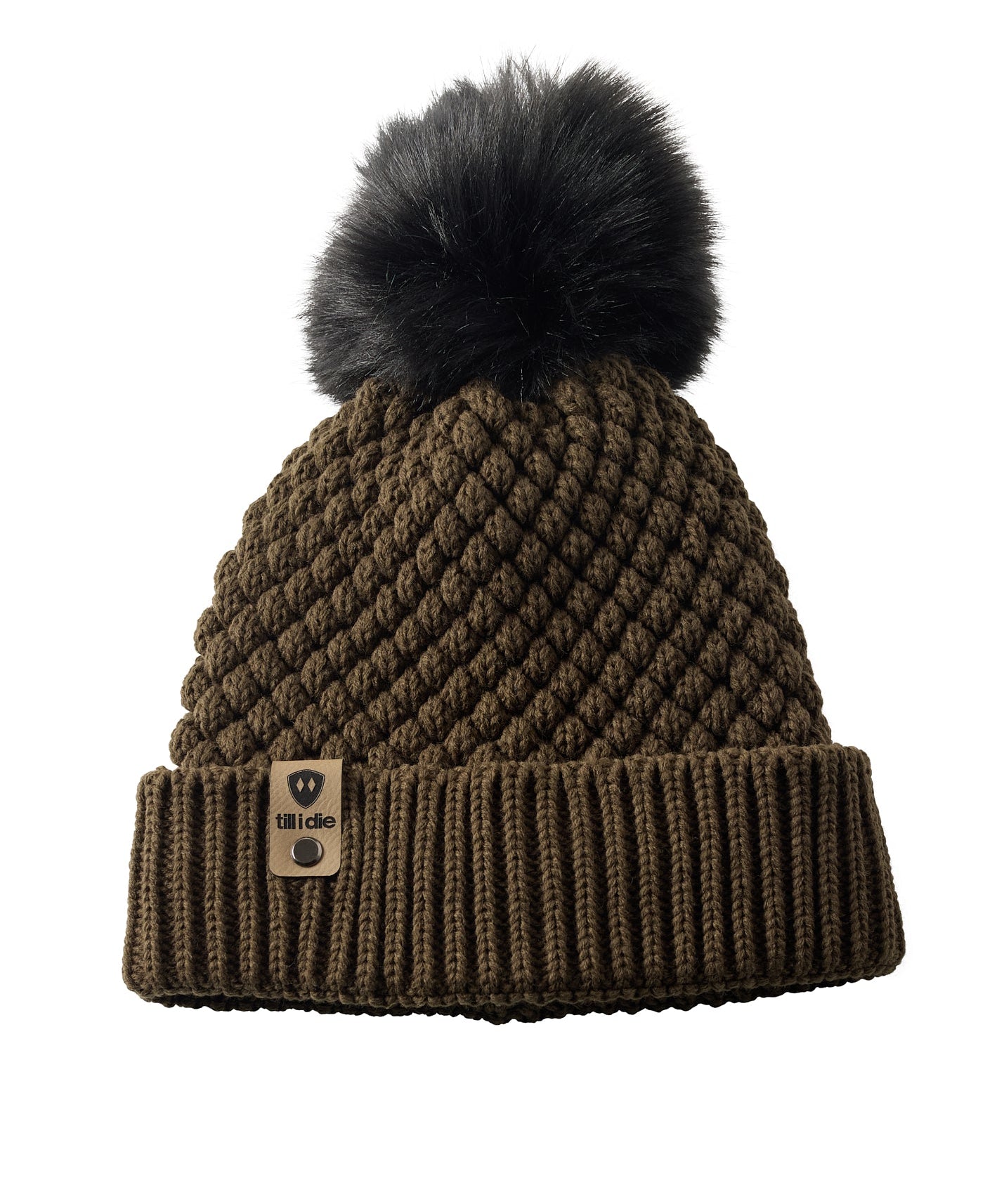 Product flat lay of the Diamond Knit Pom Beanie in military olive, displaying the ribbed cuff, diamond knit design, and leather logo tab with faux fur pom.