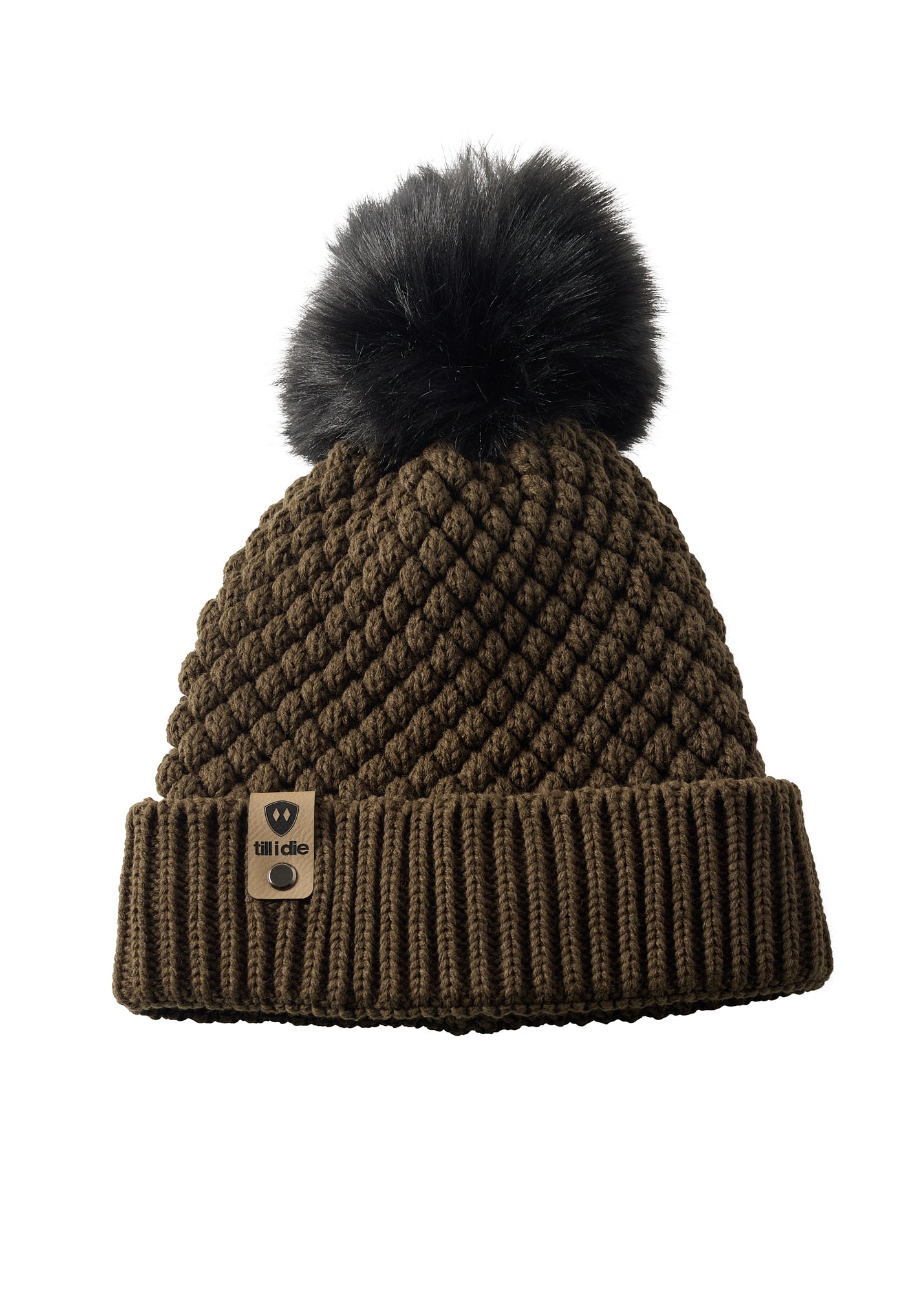 Product flat lay of the Diamond Knit Pom Beanie in military olive, displaying the ribbed cuff, diamond knit design, and leather logo tab with faux fur pom.