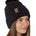 Side view of a female model wearing the black knit pom beanie hat in black on a white background. the hat features a matching pom pom, leather tab with embossed black till i die logo and nickel fastener. 