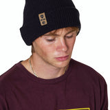 Male model wearing the Till I Die Leather Tab Knit Beanie in black, styled with the cuff folded to show the branded leather logo tab