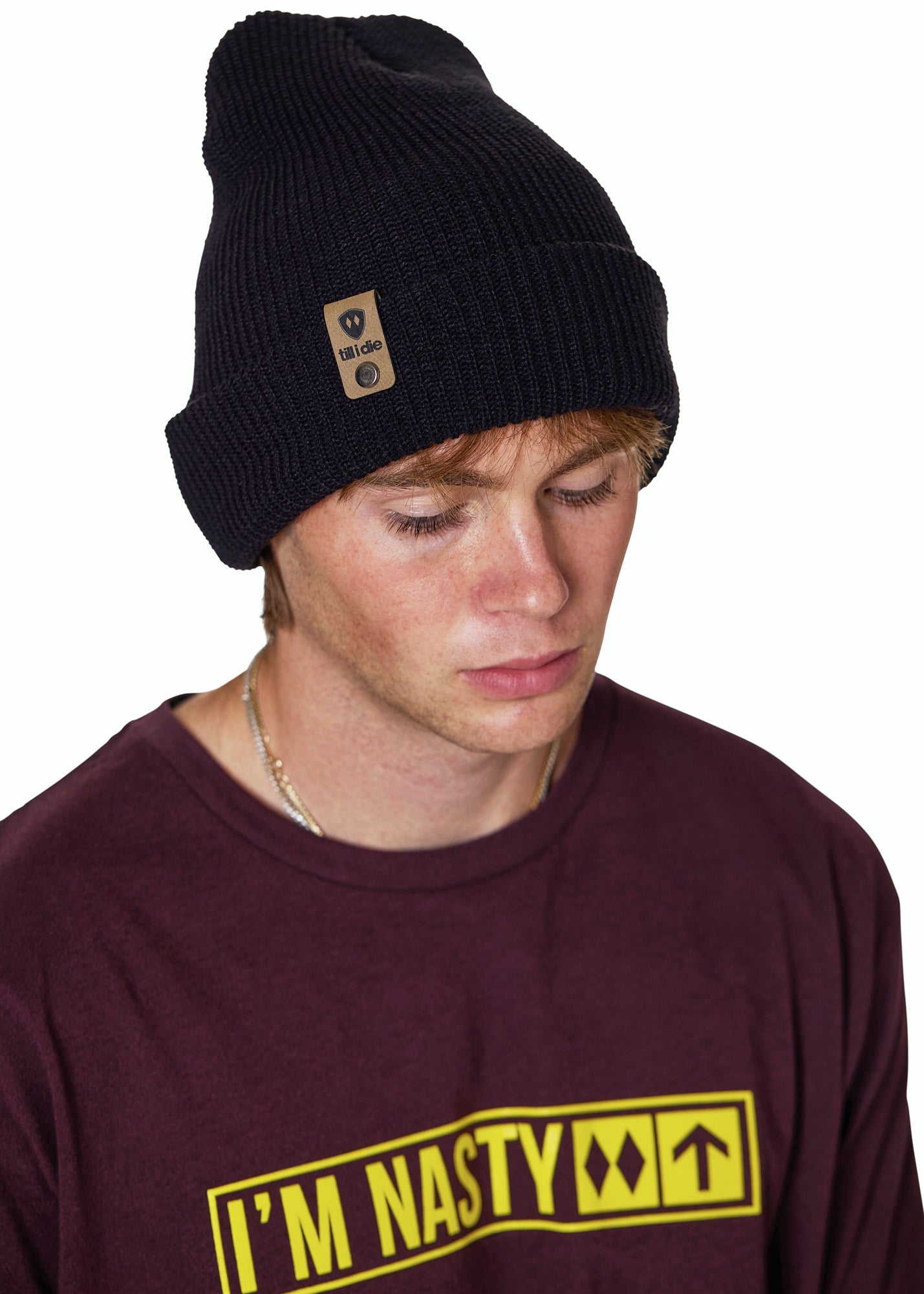 Male model wearing the Till I Die Leather Tab Knit Beanie in black, styled with the cuff folded to show the branded leather logo tab