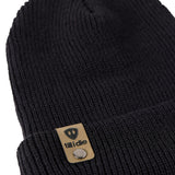 Flat lay of the Till I Die black knit beanie showing close-up detail of the medium gauge knit and branded leather logo tab on the cuff