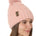 side view of a female model wearing a blush knit pom beanie featuring a matching pom pom, cuff and leather till i die logo tab with a nickel fastener.