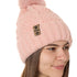 side view of a female model wearing a blush knit pom beanie featuring a matching pom pom, cuff and leather till i die logo tab with a nickel fastener.