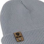 Flat lay of the Till I Die cadet blue  knit beanie showing close-up detail of the medium gauge knit and branded leather logo tab on the cuff