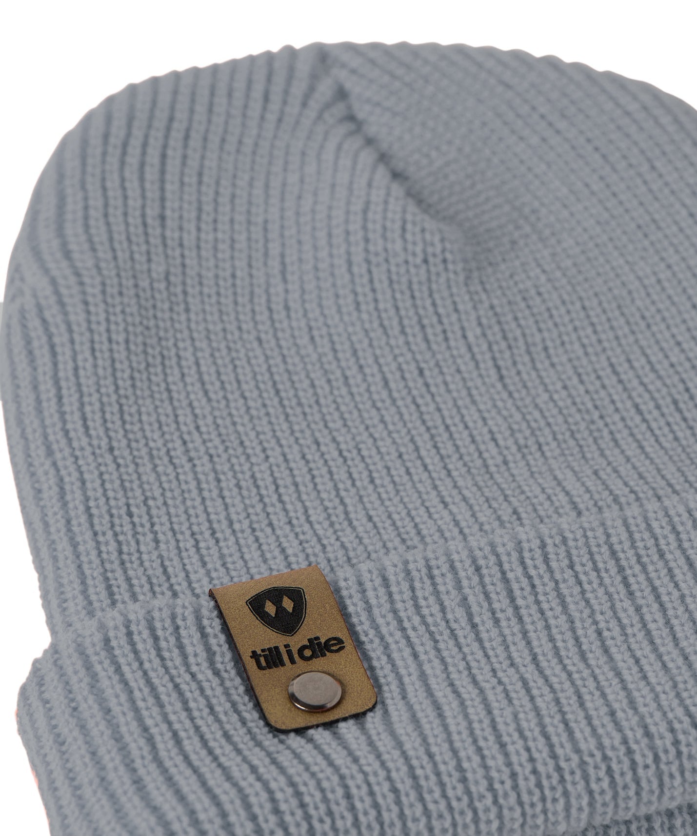 Flat lay of the Till I Die cadet blue  knit beanie showing close-up detail of the medium gauge knit and branded leather logo tab on the cuff