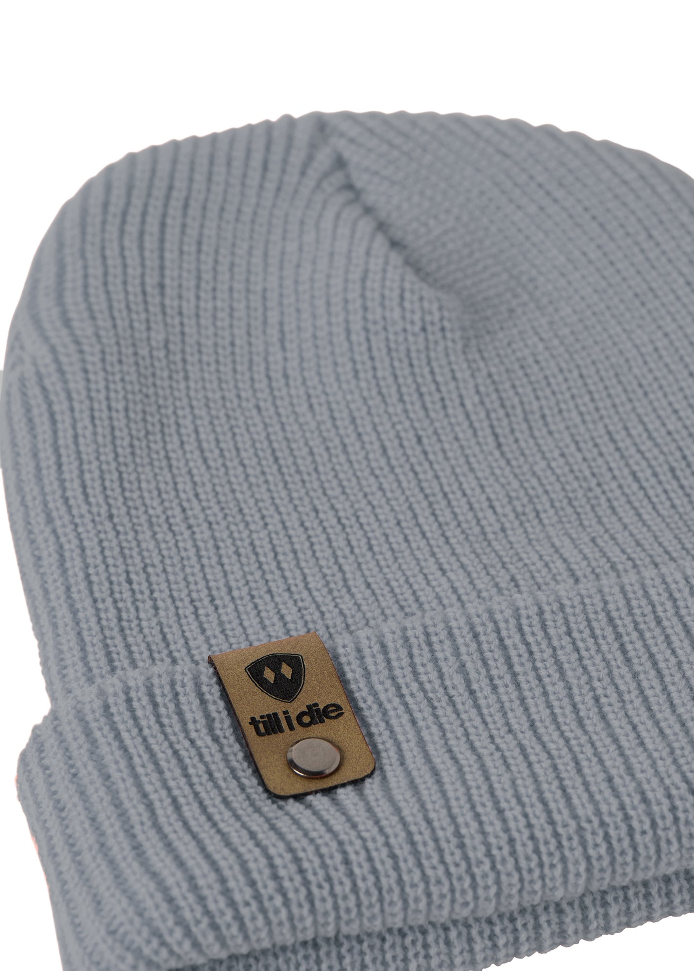 Flat lay of the Till I Die cadet blue  knit beanie showing close-up detail of the medium gauge knit and branded leather logo tab on the cuff