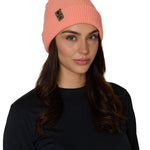 Female model wearing the Till I Die Leather Tab Knit Beanie in coral, showcasing the cozy fit and branded leather detail on the cuff