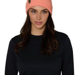 Female model wearing the Till I Die Leather Tab Knit Beanie in coral, styled with the cuff folded to show the branded leather logo tab