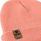 Flat lay of the Till I Die coral  knit beanie showing close-up detail of the medium gauge knit and branded leather logo tab on the cuff