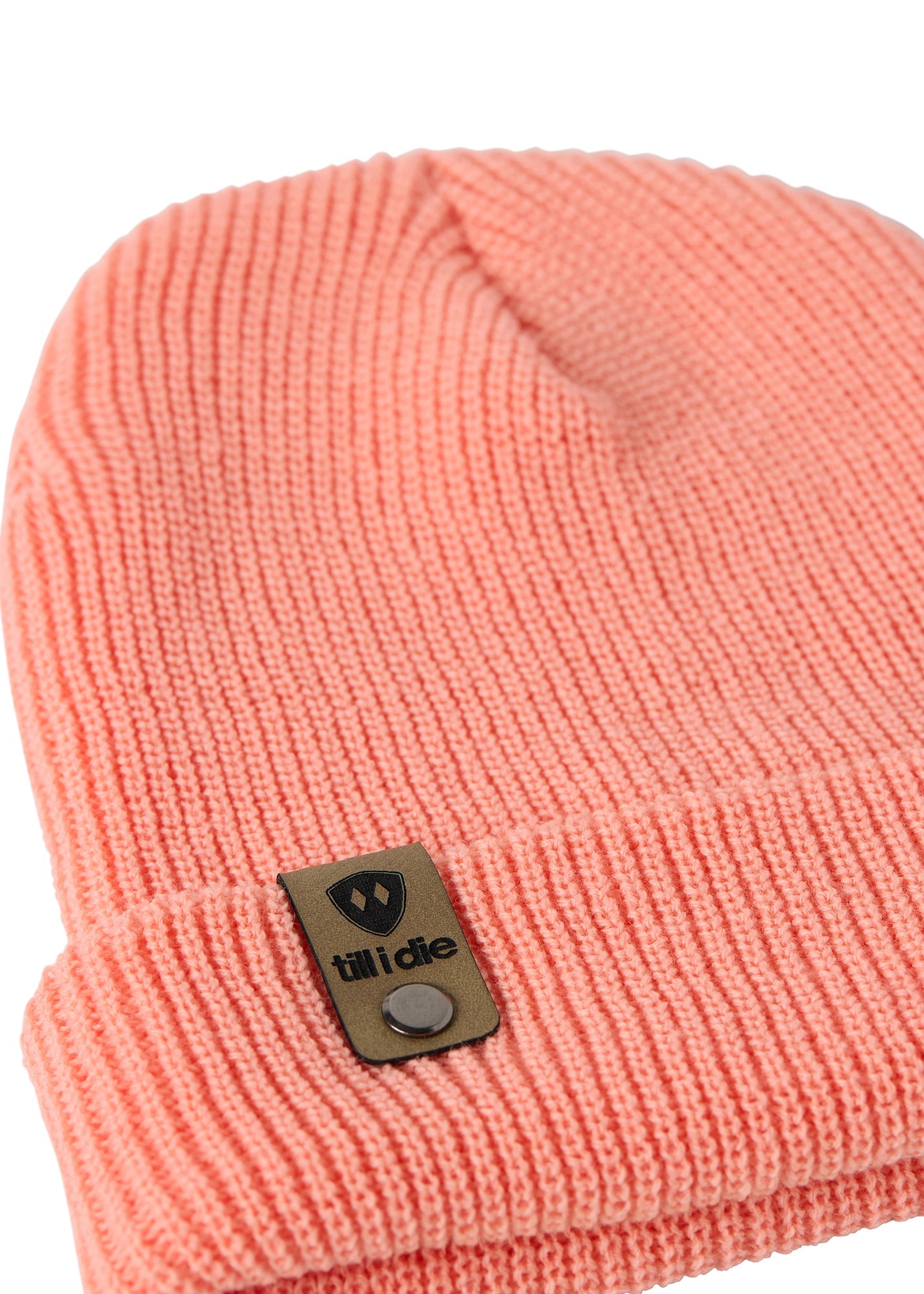 Flat lay of the Till I Die coral  knit beanie showing close-up detail of the medium gauge knit and branded leather logo tab on the cuff