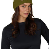 Female model wearing the Till I Die Leather Tab Knit Beanie in military green, showcasing the cozy fit and branded leather detail on the cuff