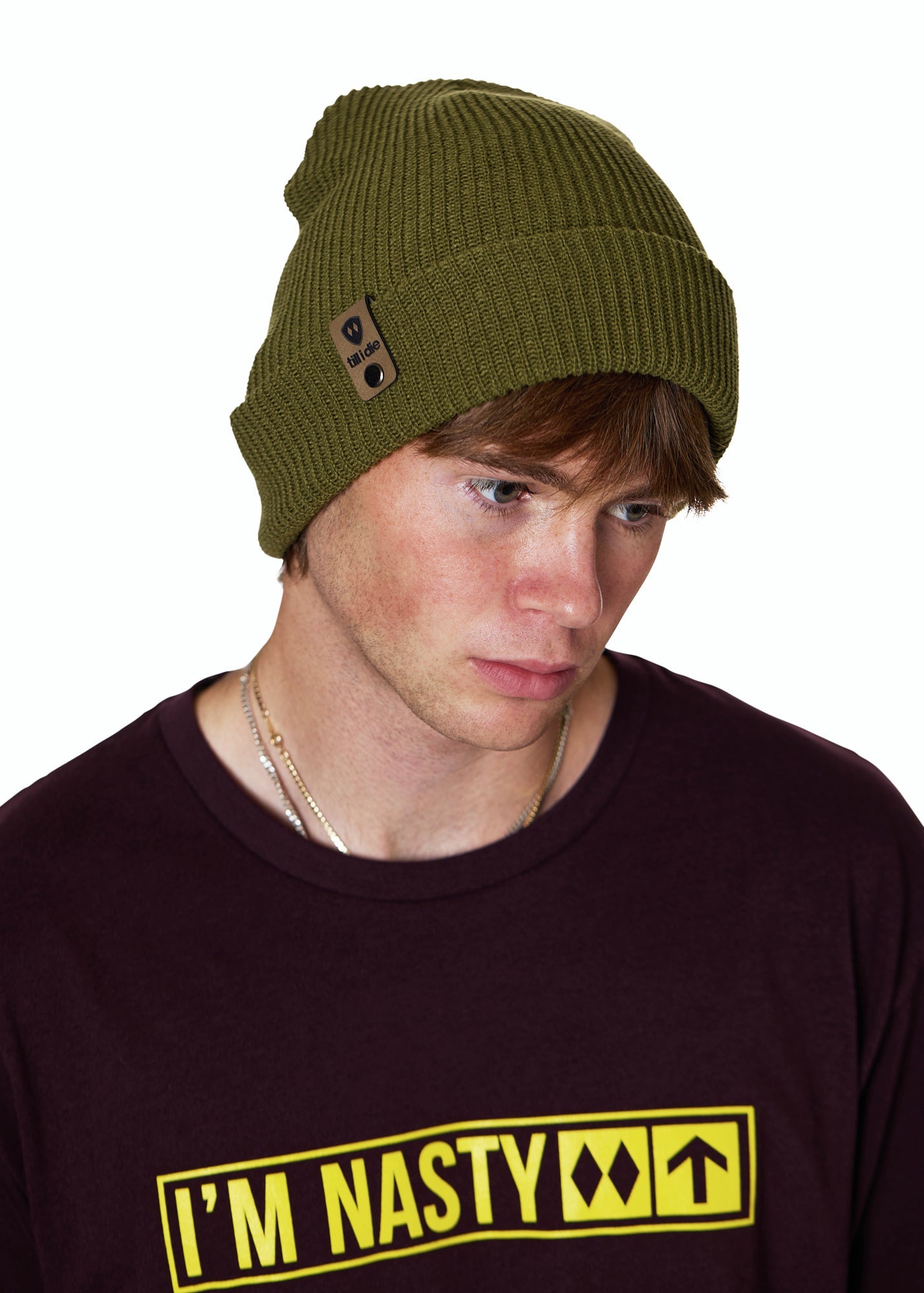 Male model wearing the Till I Die Leather Tab Knit Beanie in military green, styled with the cuff folded to show the branded leather logo tab