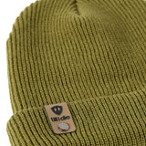 Flat lay of the Till I Die military green  knit beanie showing close-up detail of the medium gauge knit and branded leather logo tab on the cuff