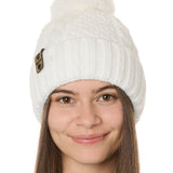 front view of a female model wearing a white knit pom beanie featuring a matching pom pom, cuff and leather till i die logo tab with a nickel fastener.